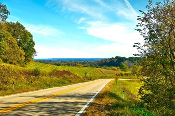 Autumn landscape road view looking downhill across fields and forests to a distant horizon in the...