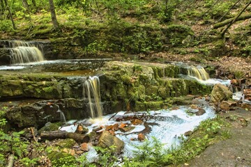 Tranquil Summer landscape of a peaceful stream forming three small waterfalls and a pool in the...