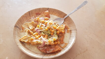 There is a plate on the table and there are samosas and a spoon in the plate 