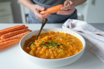 Woman serving bland food with easy to digest carrot potato soup in the kitchen
