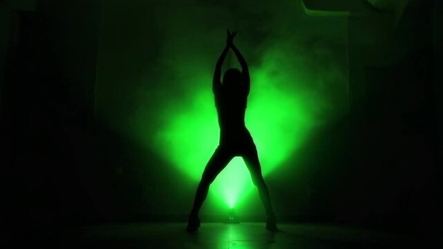 Silhouette of dancer performing under dramatic green stage lights