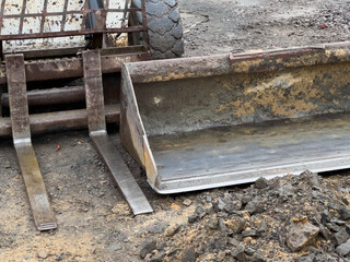 A compact loader equipped with a bucket attachment rests on a construction site, surrounded by dirt and rocks, awaiting the next earthmoving job