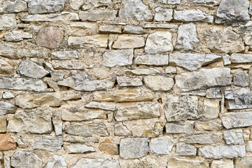 Obraz premium Background of a natural stone or sandstone masonry wall in South France. Detailed stone texture image in beige, brown, grey and green 