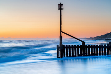 A beach groyne on the beach in Mundesley, Norfolk, UK before the sun was rising with a long...
