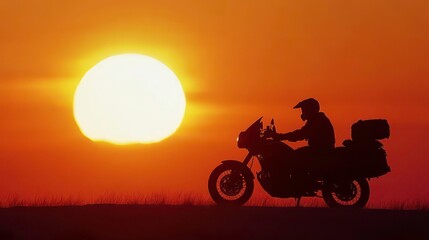 Fototapeta premium Silhouette of a motorcyclist riding into the setting sun.