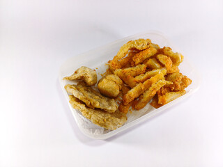 Slices of chicken katsu and pempek, a savory Indonesian fishcake delicacy, arranged in a transparent container, showcasing a fusion of crispy chicken and flavorful fishcake in a convenient display	
