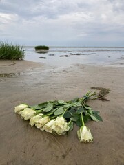 Weiße Rosen im Blumenstrauss nach Seebestattung im niedersächsischen Wattenmeer der Nordsee vor...