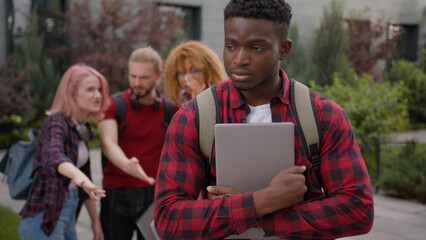 Group of angry students teenagers multiracial classmates laughing humiliate bully mockery at college university outdoors discriminate mock African American sad upset man student stressed guy problem