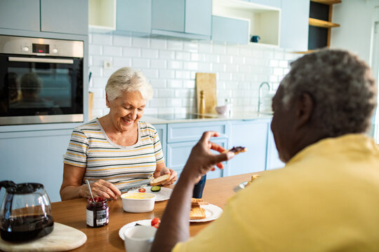 Happy senior couple eating breakfast together at kitchen table