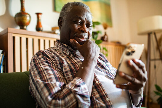 Close up of a senior black man using smartphone on home sofa