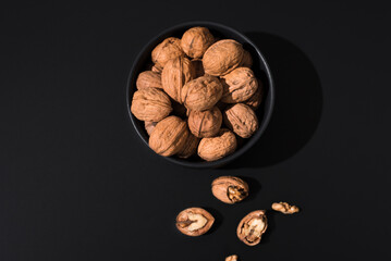 Nueces en un plato negro sobre fondo negro. Vista superior	