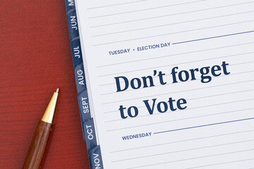 Do not forget to vote message on a Tuesday day planner with pen on desk