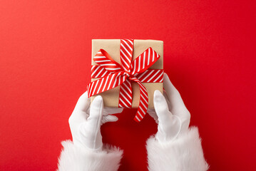 Santa Claus hands holding a beautifully wrapped present with a red and white striped ribbon, set...