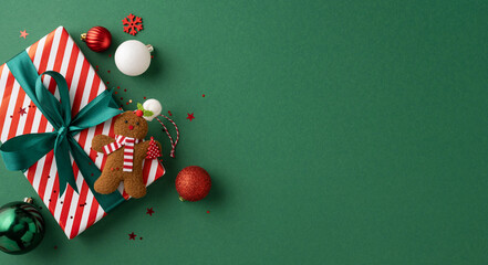 Top view of a stylish Christmas present with a gingerbread figure and various festive ornaments on a green backdrop, creating a joyful holiday mood