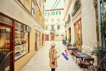 Enjoying vacation in Croatia. Young traveling woman with national croatian flag walking on Split Old Town.