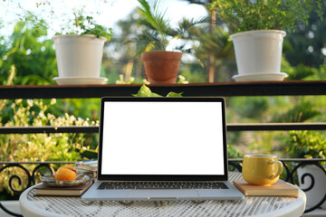 Laptop and yellow cup and dessert on white table at balcony outdoor