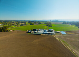 A large farm with a barn and a few houses in the background