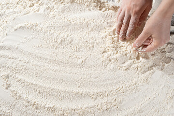 Baker working with white wheat flour, hands close-up.