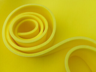 circular piece of yellow foam sponge. thin material rolled in a spiral shape