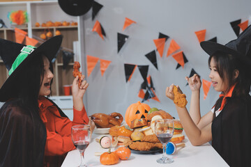 friendship, holiday and people concept - group of happy smiling friends in halloween costumes of vampire, devil, witch and cheetah at home party