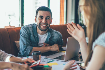 Laughing friends gathering in cafe and coworking