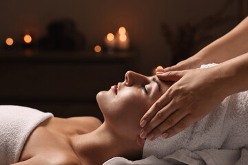 Attractive woman enjoying face massage in spa salon, closeup