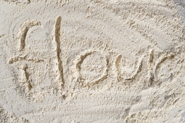 Text flour written on white wheat flour top view.