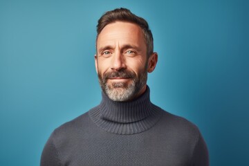 Fototapeta premium Portrait of a satisfied man in his 40s wearing a classic turtleneck sweater isolated in pastel blue background