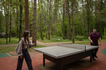 Fototapeta premium Ping pong players playing table tennis, woman and man in action, outdoor fitness and leisure.