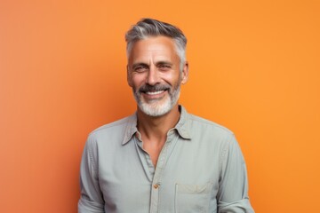 Obraz premium Portrait of a glad man in his 50s sporting a versatile denim shirt on pastel orange background