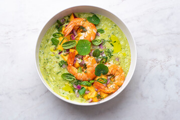 Green avocado gazpacho with shrimp and herbs, basil, lime, peaches, nasturtium leaves and purple onions. Spring and summer cuisine, healthy recipes full of proteins, fats and vitamins. Fresh seafood