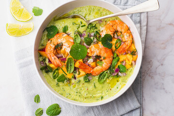 Green avocado gazpacho with shrimp and herbs, basil, lime, peaches, nasturtium leaves and purple onions. Spring and summer cuisine, healthy recipes full of proteins, fats and vitamins. Fresh seafood