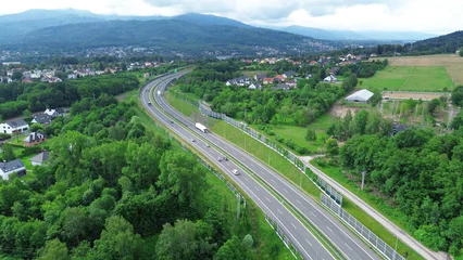 Selbstklebende Fototapeten Blue Jeans Highway through rural landscape with hills and mountains  © AlexGo