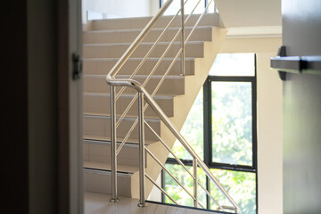 Fire exit metal door in opening position with background of the stairway with railing handle, using...