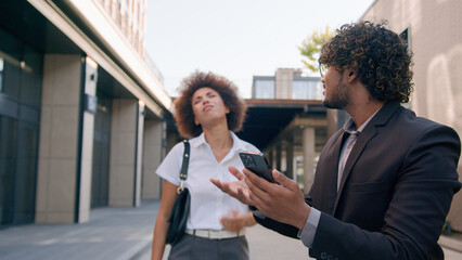 Business multiracial colleagues coworkers walk in city Indian man Arabian businessman with African American woman businesswoman lost mobile phone failure crash bad news smartphone problem frustrated
