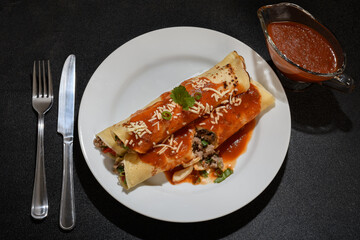 Meat pancake on a white plate with red sauce, dark background