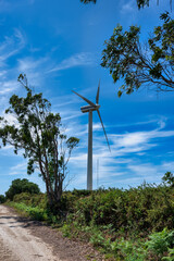 Low-angle view of a modern wind turbine against a bright blue sky, symbolizing renewable energy