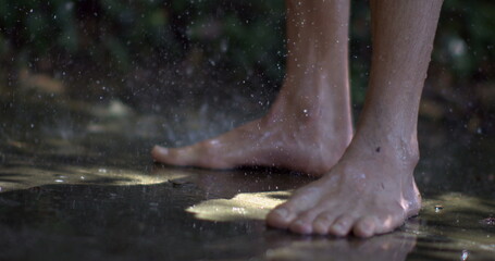 Fototapeta premium Close-up of wet feet in slow-motion, water droplets splashing around as they step on a wet surface, highlighting a refreshing summer moment