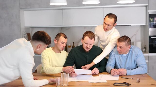 Troubled man reading legal notice surrounded by friends providing moral support sitting at table n home kitchen during informal friendly meeting