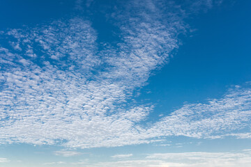 A beautiful, clear blue sky with wispy white clouds, gently rolling across the sky