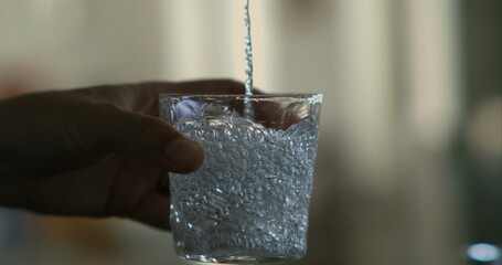Hand pouring water into glass in slow-motion at 800 fps, emphasizing detailed bubbles and water...