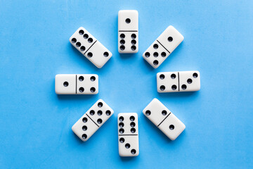 The game of dominoes is a table game involving rectangular pieces with dots that represent numbers. The objective is to match tiles with matching numbers. Photo with blue background.