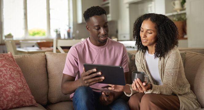 Smiling young multiracial couple using a digital tablet on a sofa