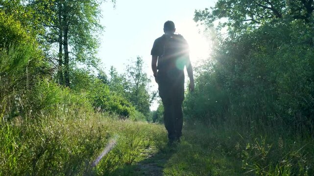 Man is hiking farther down a path through nature