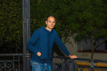 A guy stands in a gazebo in the park next to a backpack	
