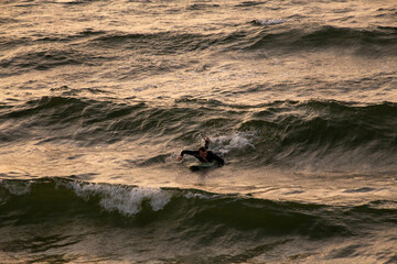 Surfer paddles out onto a small wave in the Baltic Sea