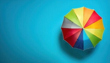 Obraz premium Overhead Top View of a Multicolored Umbrella on a Bright Blue Background. Ideal for Concepts of Summer, Creativity, Protection, and Playful Vibes in Marketing, Graphic Design, and Lifestyle Imagery
