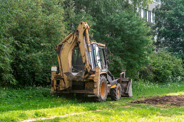 A large yellow and orange construction vehicle is parked in a grassy field. The vehicle is a...