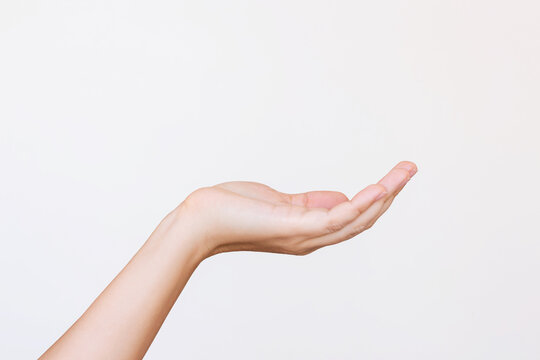 A young woman's outstretched hand making a gesture like holding something or asking for help isolated on a white background. Mockup with empty copy space for a intended object