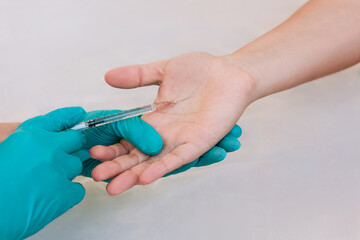 Doctor's hands in blue gloves injecting the botulinum toxin that treats hyperhidrosis into the woman's palm using syringe needle. Treatment of excessive sweating